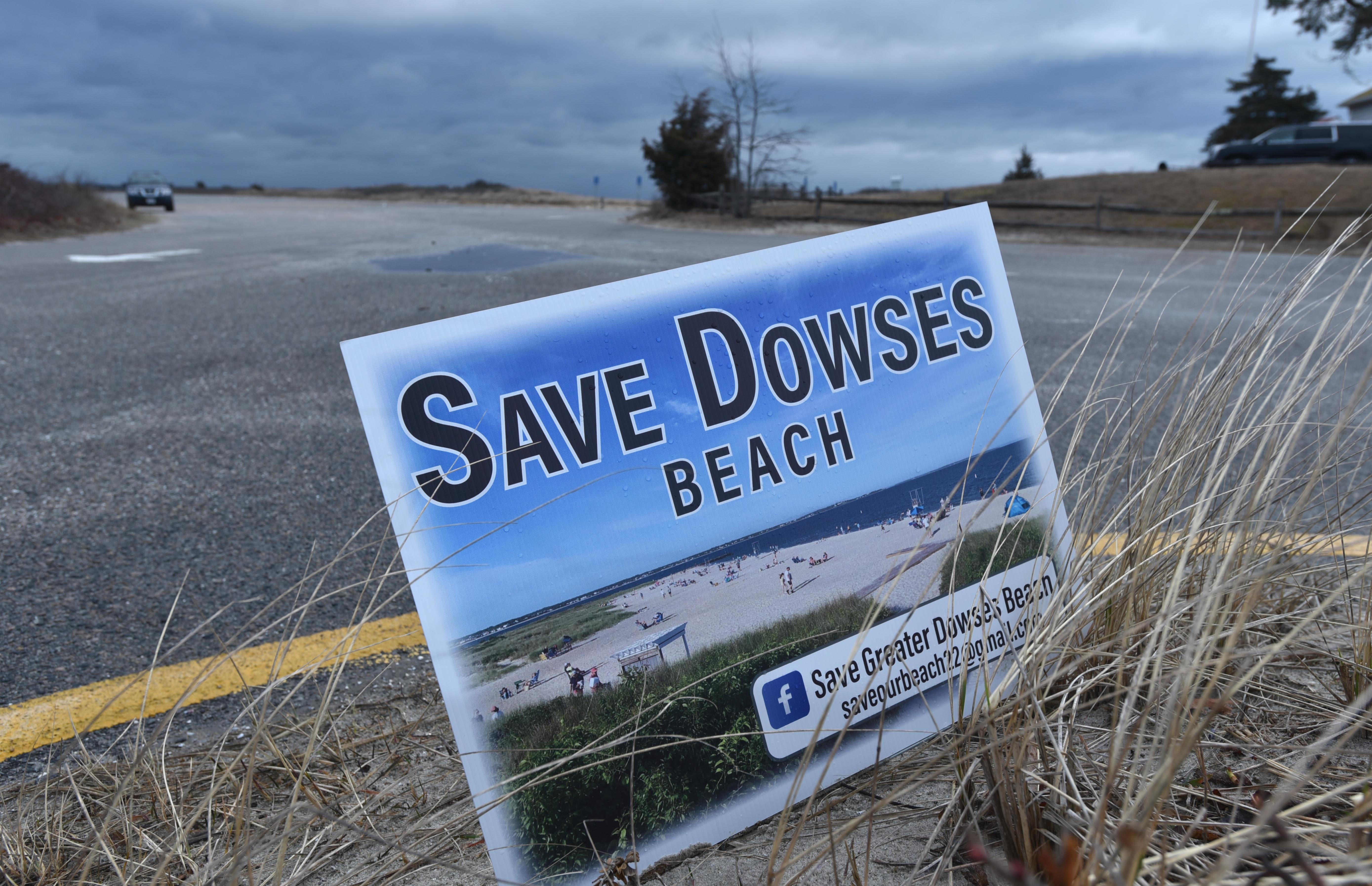 A "Save Dowes Beach" sign flutters in a strong north wind on Wednesday at the entrance to Dowses Beach in Osterville, the landfall location for the proposed offshore wind farm Commonwealth Wind. A group opposed to using the beach for the cable landfall has posted signs around the village.