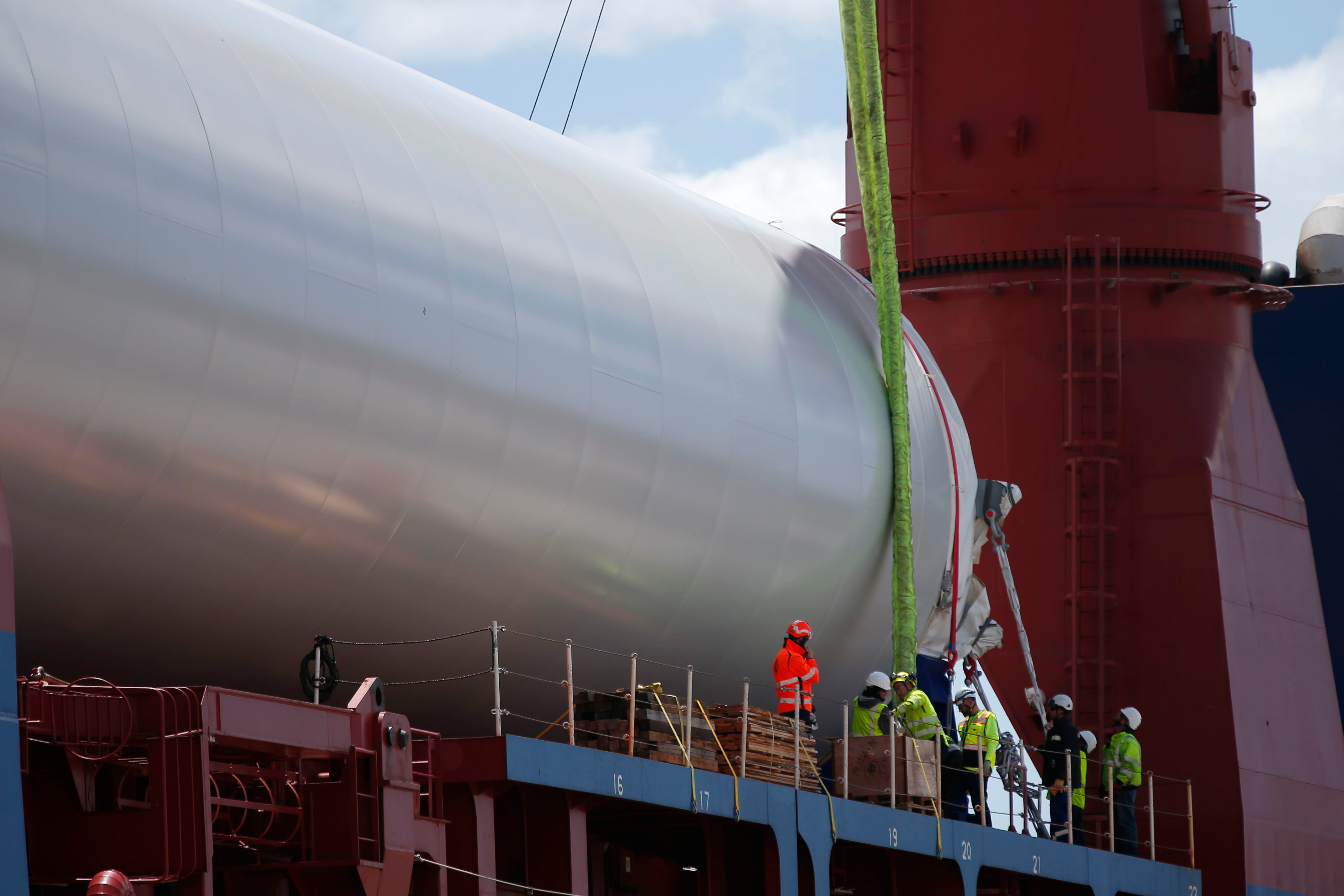 Longshoremen work on attaching straps to one of three sections of the mast of a wind turbine which arrived aboard the first ship carrying turbine components for Vineyard Wind at the Marine Commerce Terminal in New Bedford.