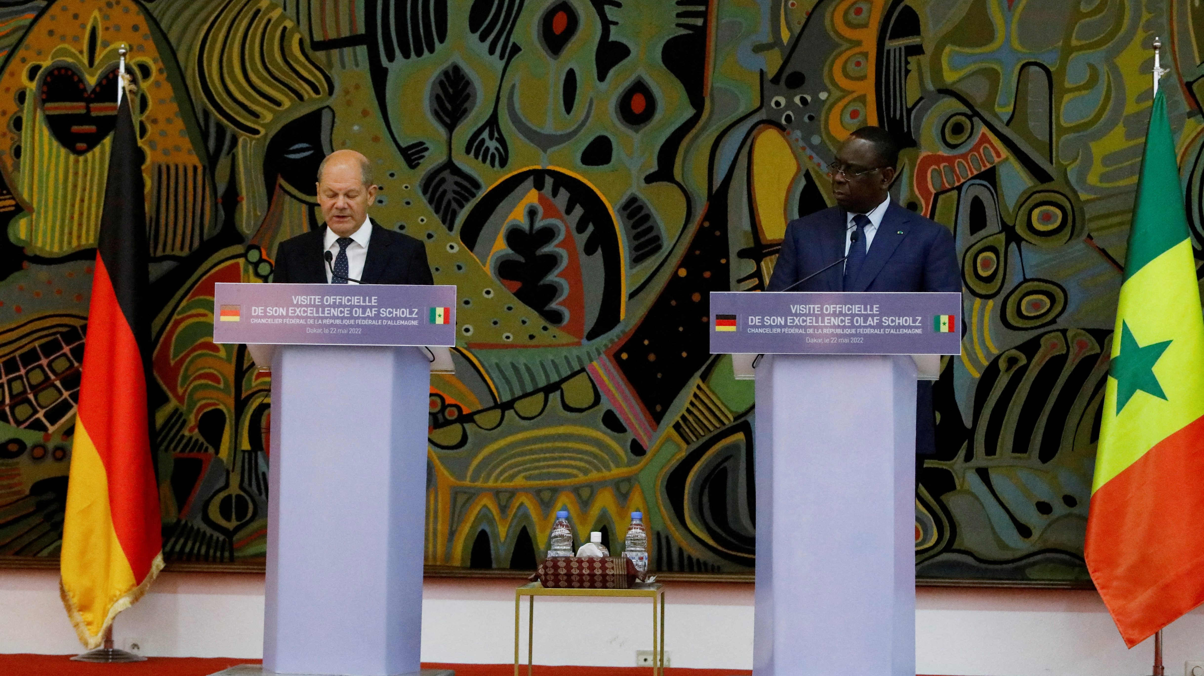 German Chancellor Olaf Scholz, and Senegal's president Macky Sall standing on separate lecterns during a news conference