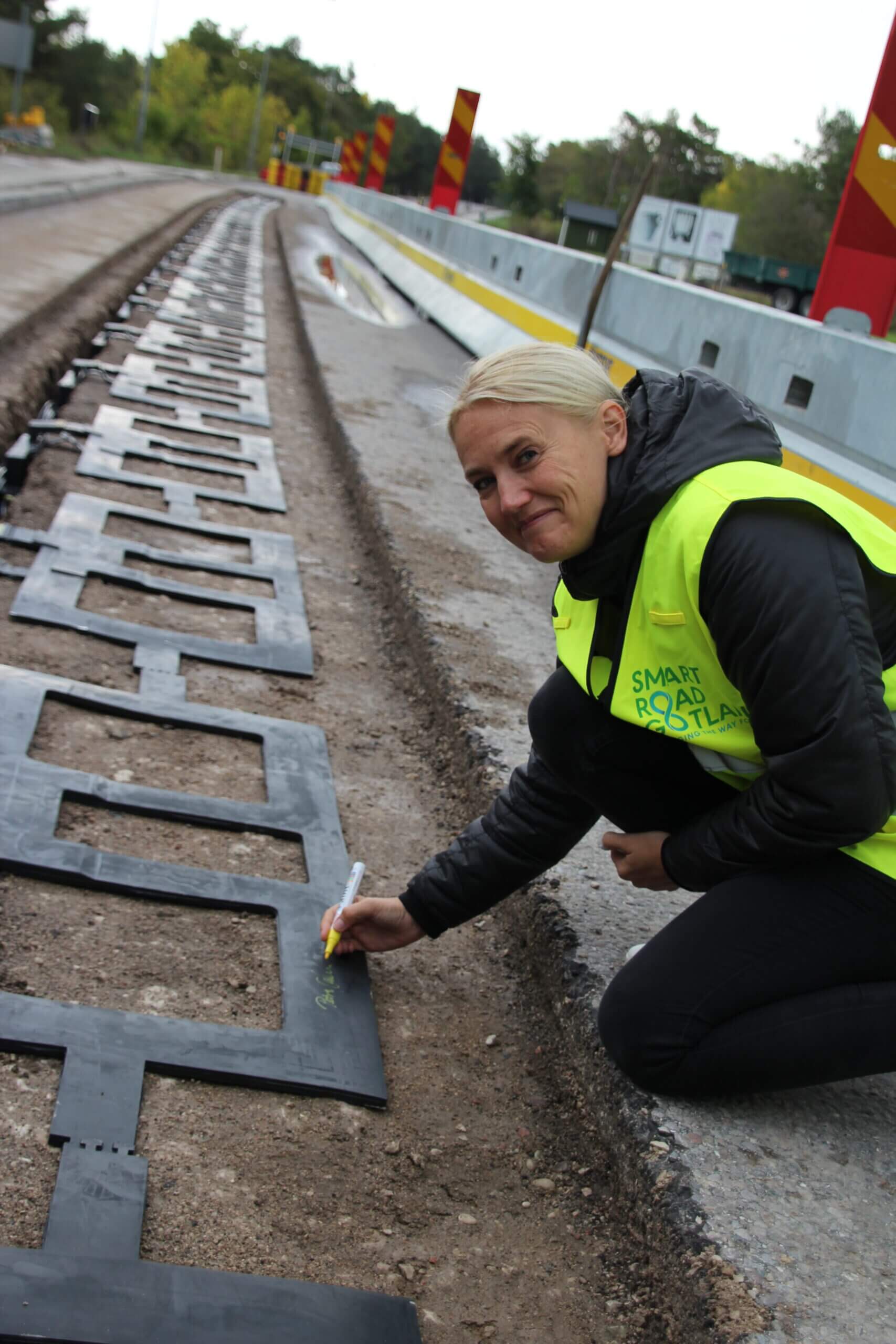 Electreon worker laying out inductive coils for wireless in-road EV charging in Sweden.