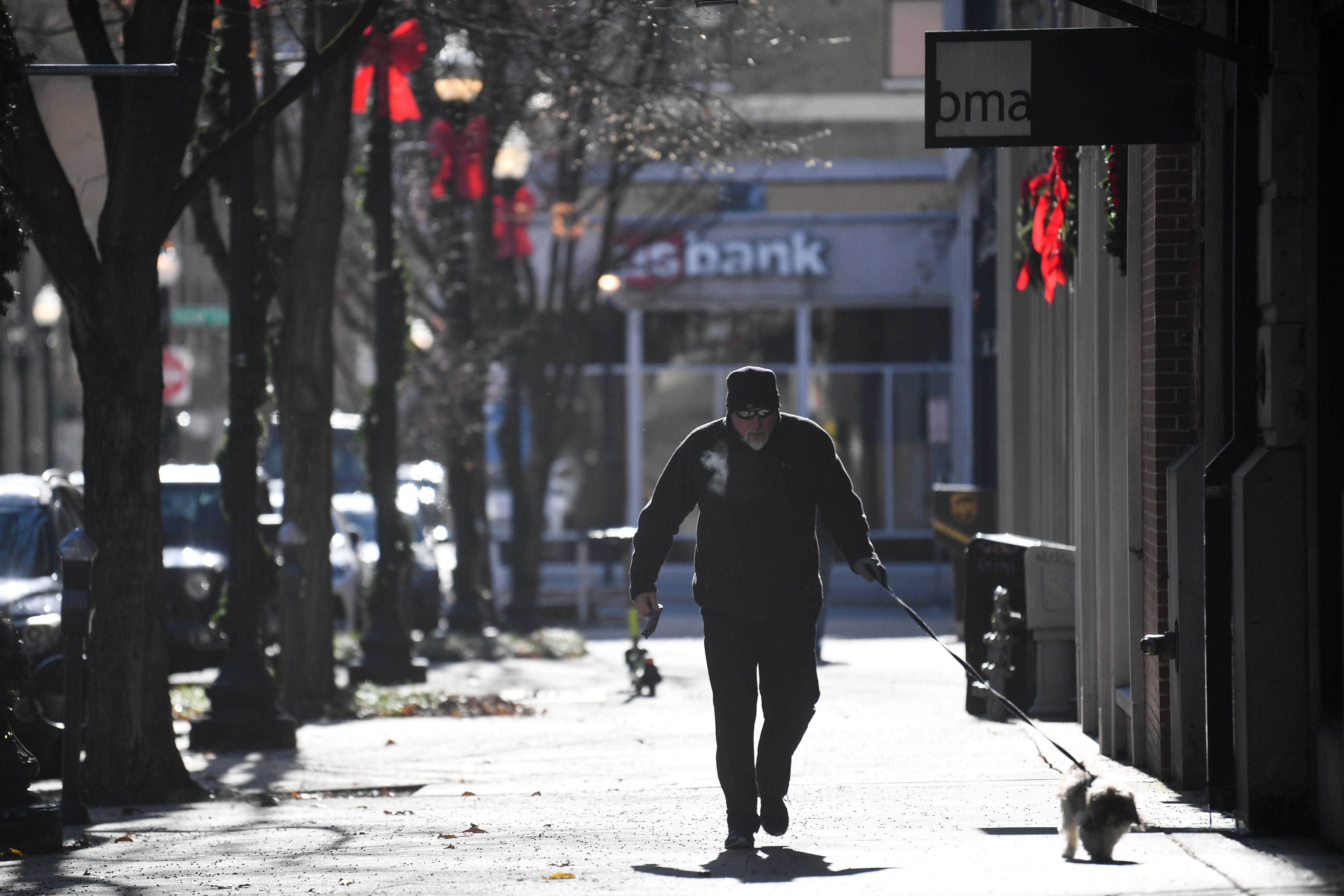 A man walks his dog near Market Square in downtown Knoxville on Dec. 23. The temperature hovered around 7 degrees early that day after a winter storm moved into the region.