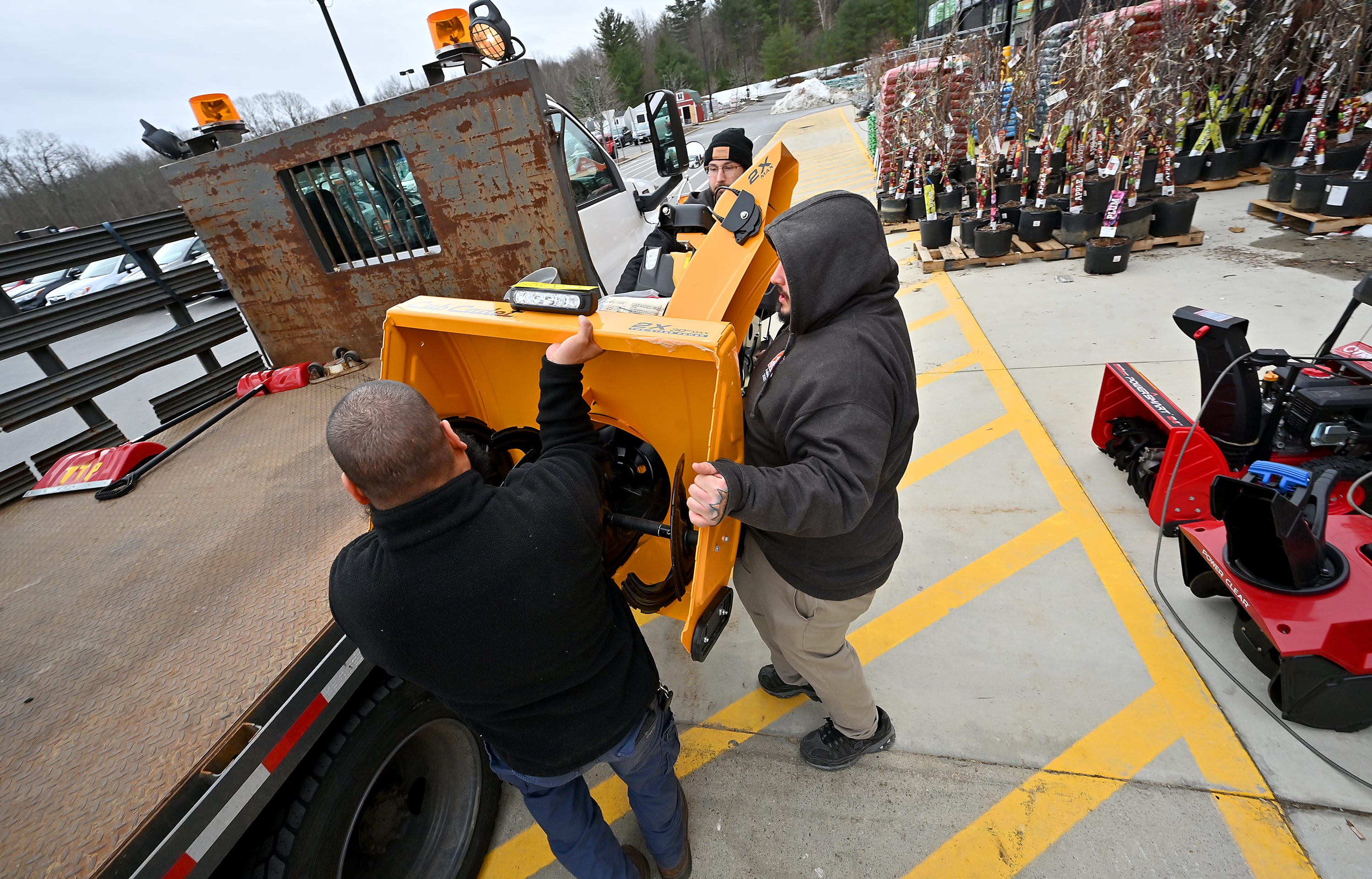 Home Depot employees Matthew Bregman, back, and Josh Marin, center, help Table Talk Pies Facilities Supervisor Marccus Rosado, front, load a large snowblower onto a truck Monday morning in Auburn.