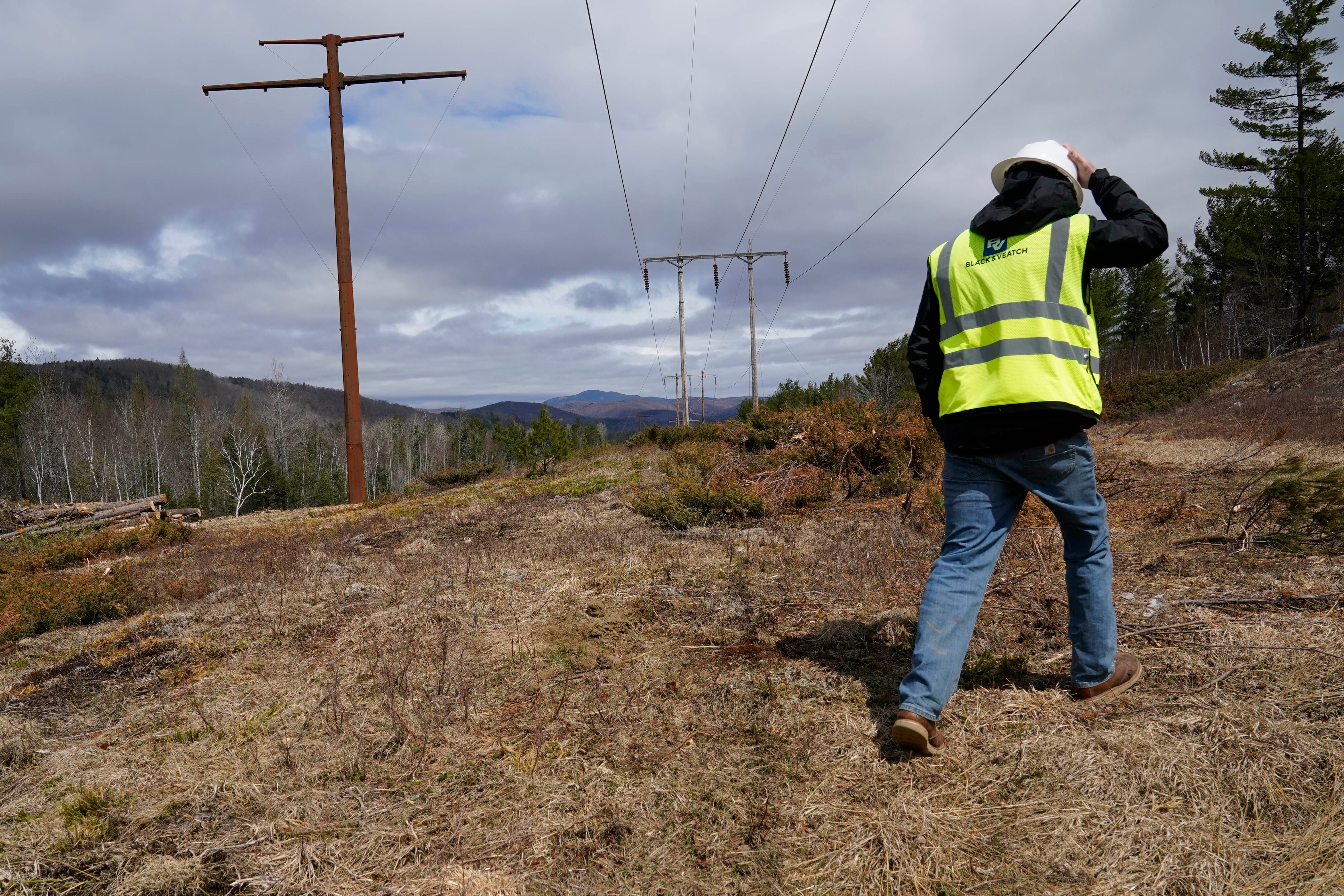 A worker inspects a Central Maine Power electricity corridor that has been widened to make way for new utility poles, April 26, 2021, near Bingham, Maine. Voters rejected a $1 billion transmission line but that is not the end of the polarizing project in the woods of western Maine.